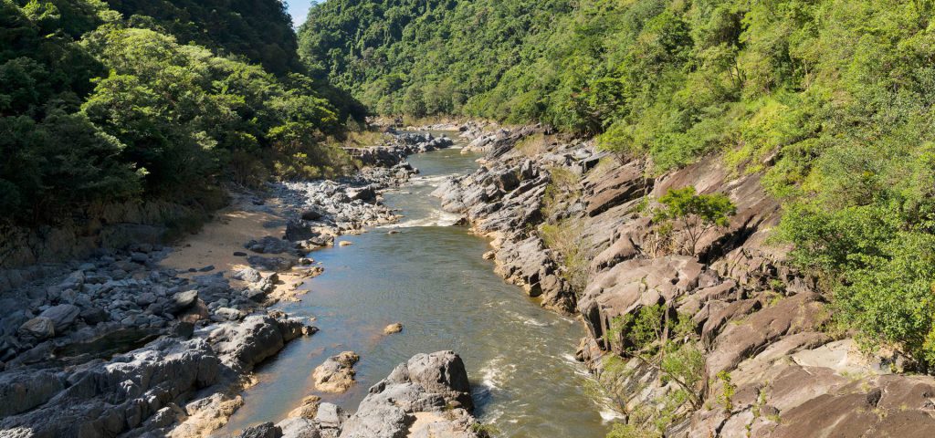 A photograph of the Barron River near Barron Gorge Power Station. The river is dotted with rocks and trees.