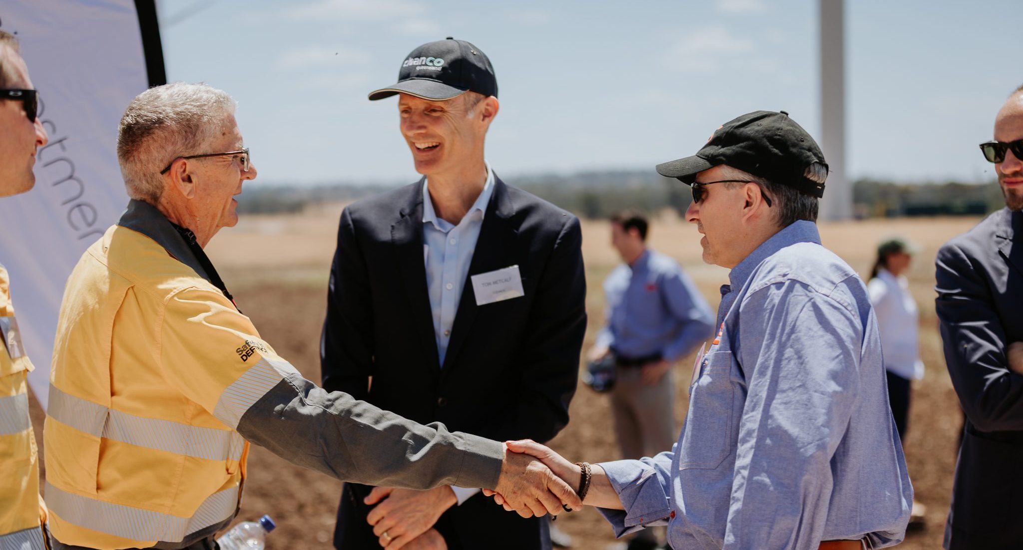 CleanCo CEO smiling as he meets the community at the opening of the Dulacca Wind Farm. He is standing behind community members as they shake hands.