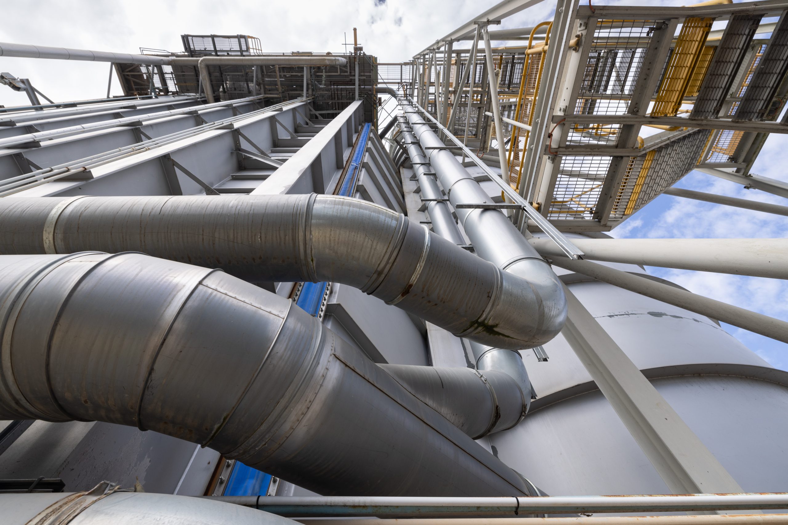 A photograph looking from the ground up towards the sky showing metal piping at Swanbank Power Station.