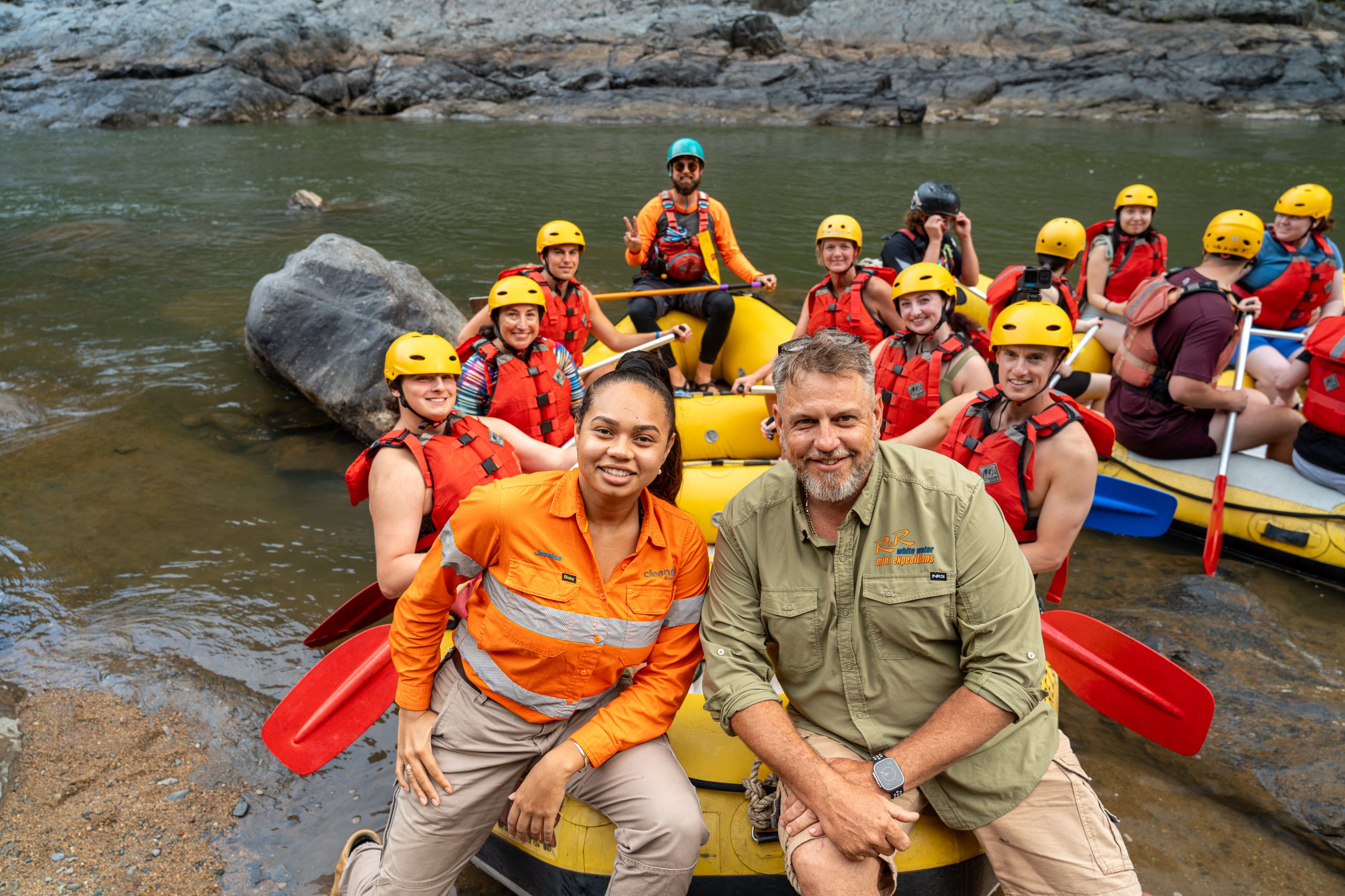 A photograph of a large group of people about to go white water rafting on the Barron River, smiling at the camera