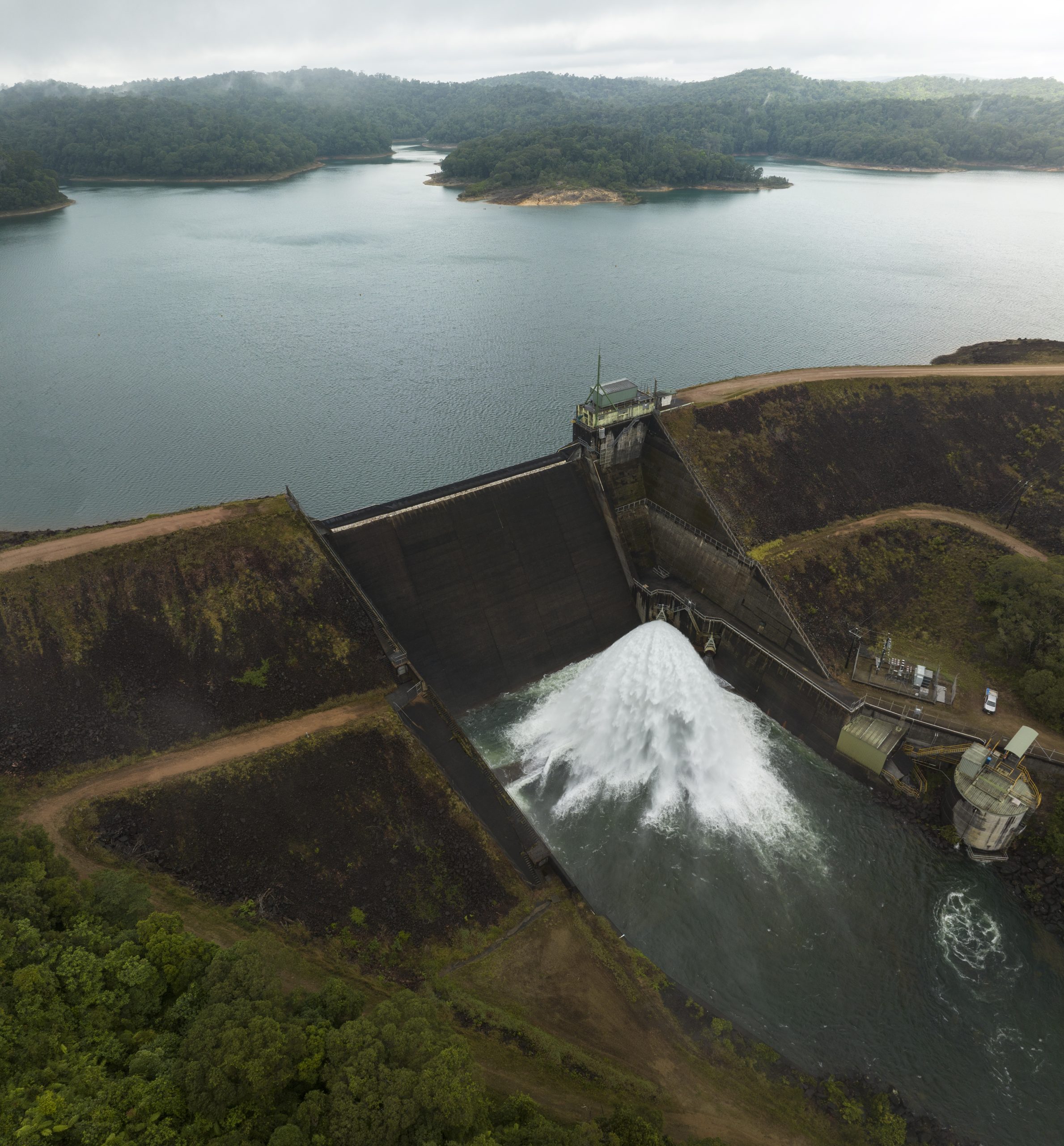 Aerial photo of Koombooloomba Dam releasing water on a cloudy day.