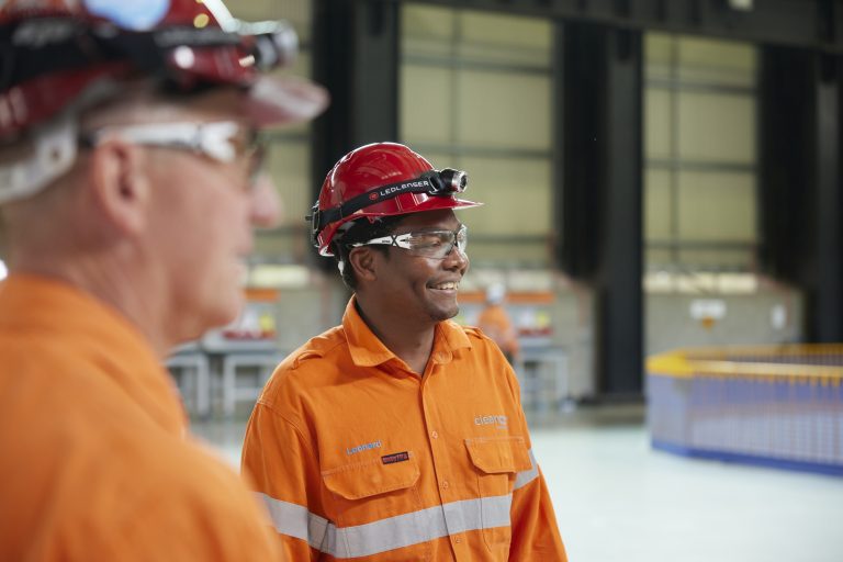 Two CleanCo employees smiling and wearing high vis clothing and hard hats look off to the side